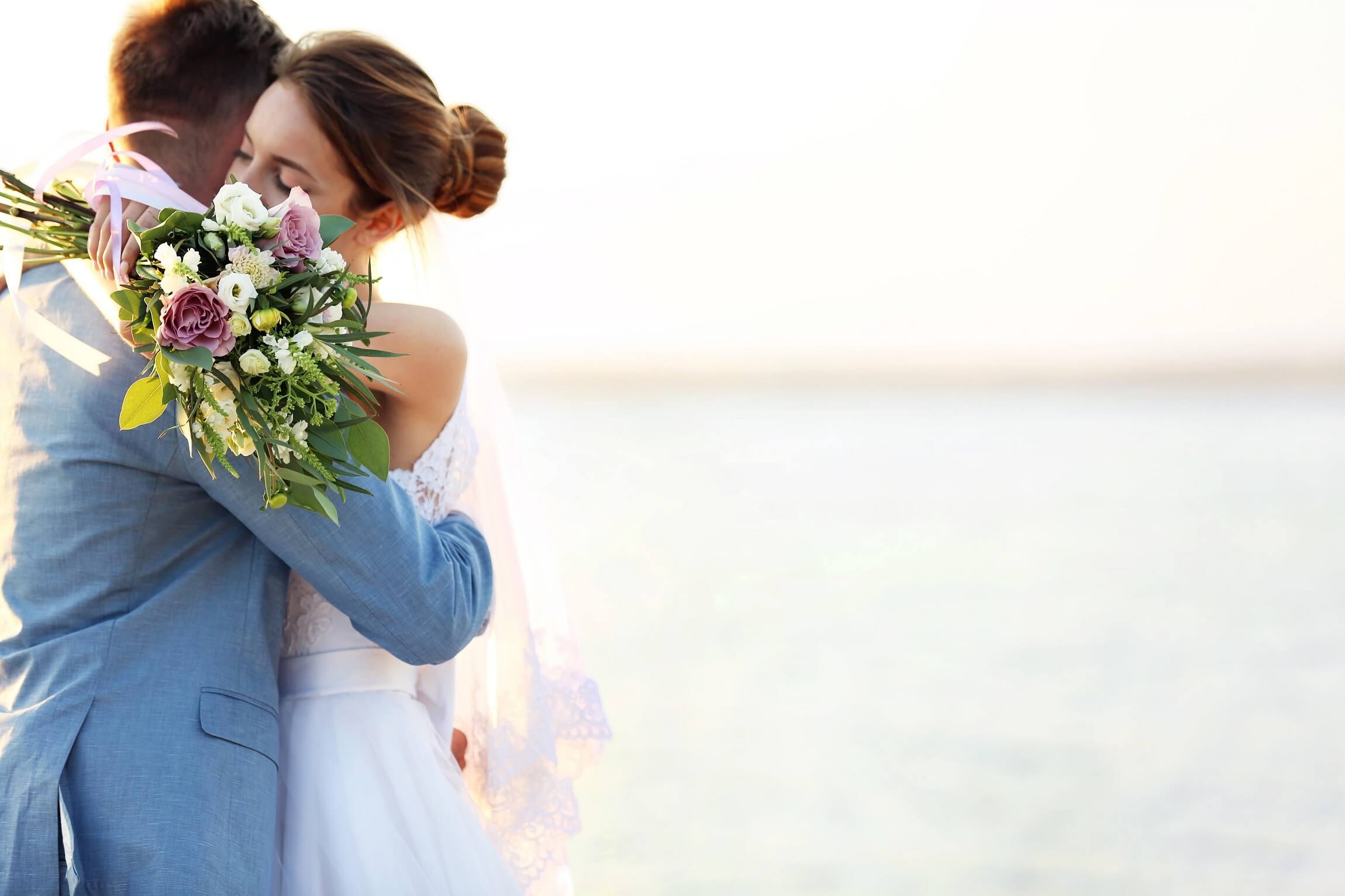 Couple embracing at golden hour with a lush bouquet